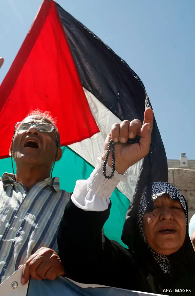 Palestinians hold national flag and shout slogans during a protest against continuing of 'Judaization of Jerusalem' by Jewish settlers and confiscating Palestinian lands at Damascus gate after Friday prayer in east jerus...
