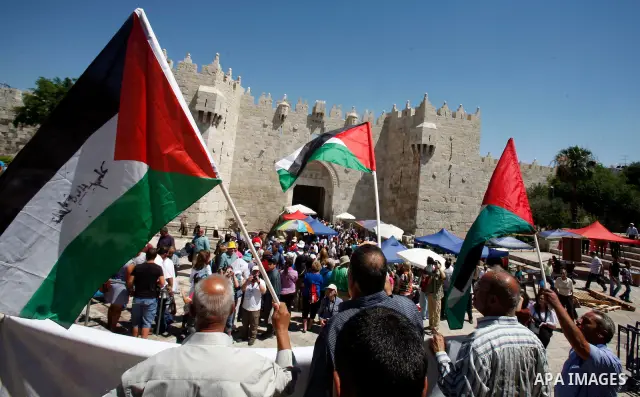 Palestinians hold national flag and shout slogans during a protest against continuing of 'Judaization of Jerusalem' by Jewish settlers and confiscating Palestinian lands at Damascus gate after Friday prayer in east jerus...
