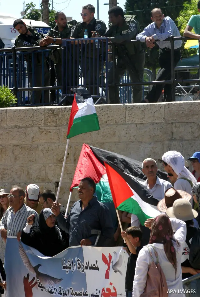 Palestinians hold national flag and shout slogans during a protest against continuing of 'Judaization of Jerusalem' by Jewish settlers and confiscating Palestinian lands at Damascus gate after Friday prayer in east jerus...
