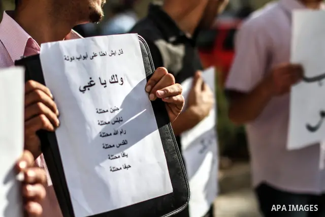 Palestinians hold banners and call the drivers to blow their horns during a demonstration solidarity with Palestinian prisoners whose still on hunger strike in Israeli jails, in the West Bank city of Ramallah, on 10 June...