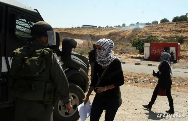 Israeli police keep guard as female Palestinian protestors fly their national flag and hold pictures of jailed Palestinian football player Mahmud Sarsak and prisoners Akram Rikhawi and Samir al-Baraka during a demonstrat...