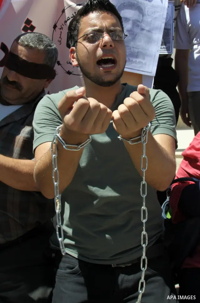 Palestinian protestors hold pictures of Palestinian prisoners Mahmoud Al-Sarsak and Akram al-Rikhawi, whose are still refusing food for 86 days after a deal was made to end a mass prisoner hunger strike, during a demonst...