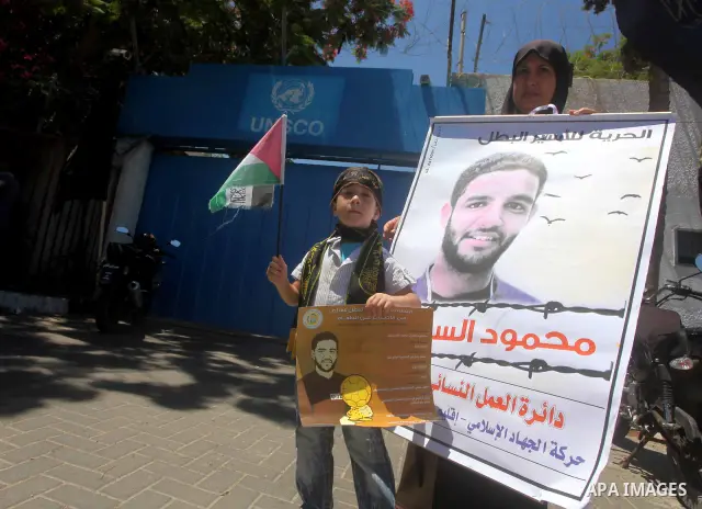 A Palestinian child holds pictures of Palestinian prisoners Mahmoud Al-Sarsak and Akram Al-Rikhawi, whose are still refusing food for 86 days after a deal was made to end a mass prisoner hunger strike, during a demonstra...