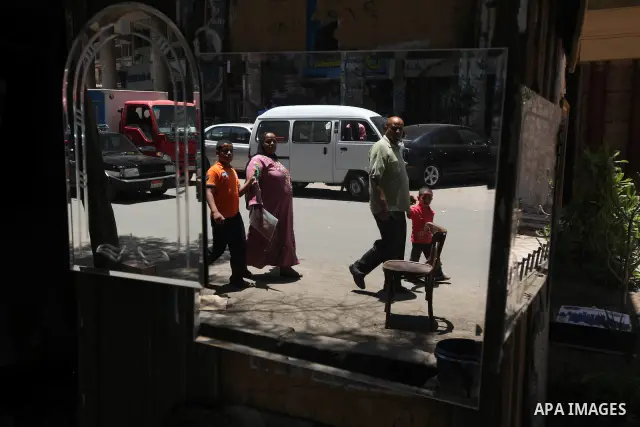 Egyptians are seen walking in the reflection of a mirror in Cairo's al-Sayeda Zenab district on June 12, 2012. A few days before the second round of the historical elections between Egypt's Muslim Brotherhood candidate M...