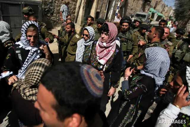 Israeli soldiers and border police try to arrest a demonstrator wearing a traditional Palestinian dress during a demonstration on al-Shuhada street against the closure of the central street in the West Bank town of Hebro...