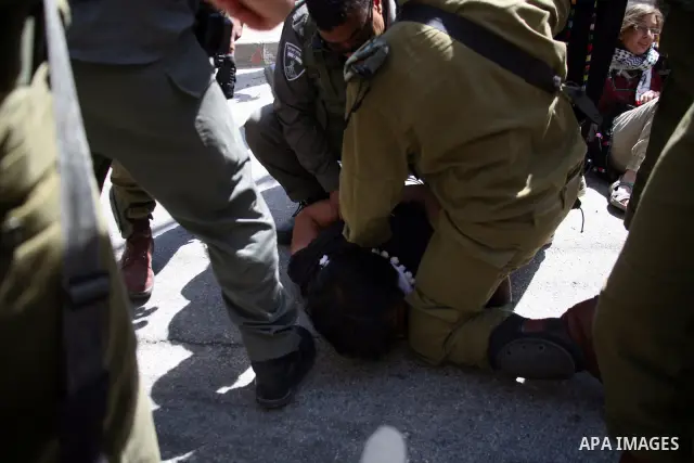 Israeli soldiers and border police try to arrest a demonstrator wearing a traditional Palestinian dress during a demonstration on al-Shuhada street against the closure of the central street in the West Bank town of Hebro...