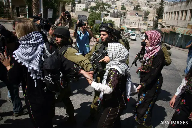 Israeli soldiers and border police try to arrest a demonstrator wearing a traditional Palestinian dress during a demonstration on al-Shuhada street against the closure of the central street in the West Bank town of Hebro...