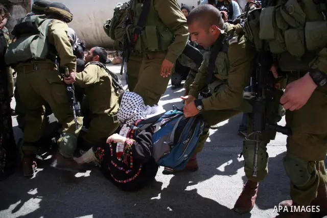 Israeli soldiers and border police try to arrest a demonstrator wearing a traditional Palestinian dress during a demonstration on al-Shuhada street against the closure of the central street in the West Bank town of Hebro...