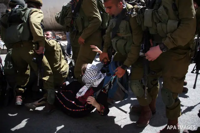 Israeli soldiers and border police try to arrest a demonstrator wearing a traditional Palestinian dress during a demonstration on al-Shuhada street against the closure of the central street in the West Bank town of Hebro...