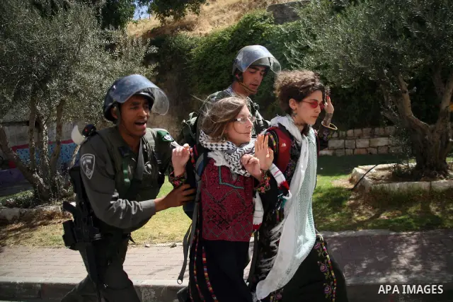 Israeli soldiers and border police try to arrest a demonstrator wearing a traditional Palestinian dress during a demonstration on al-Shuhada street against the closure of the central street in the West Bank town of Hebro...
