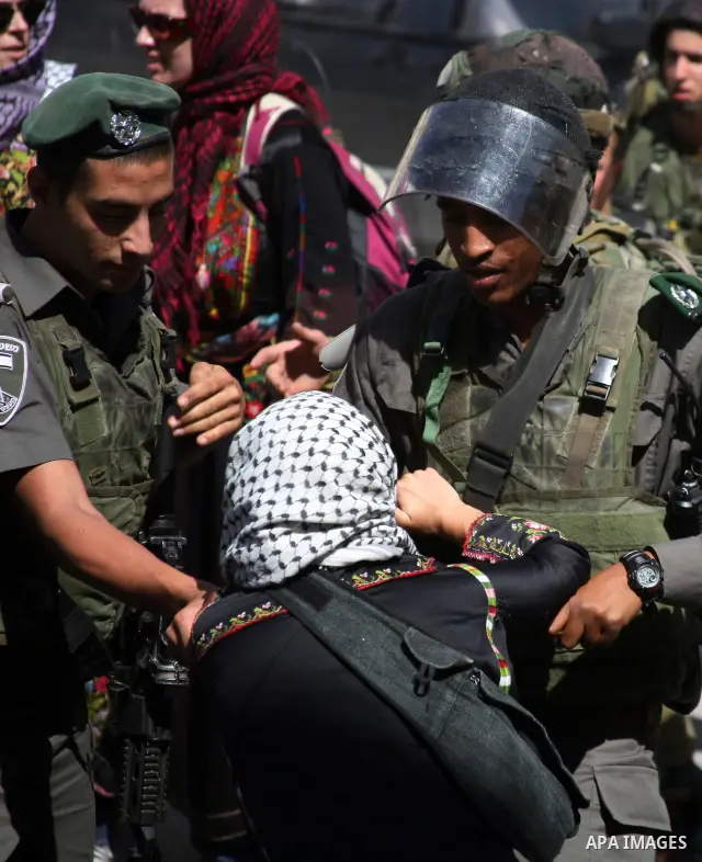 Israeli soldiers and border police try to arrest a demonstrator wearing a traditional Palestinian dress during a demonstration on al-Shuhada street against the closure of the central street in the West Bank town of Hebro...