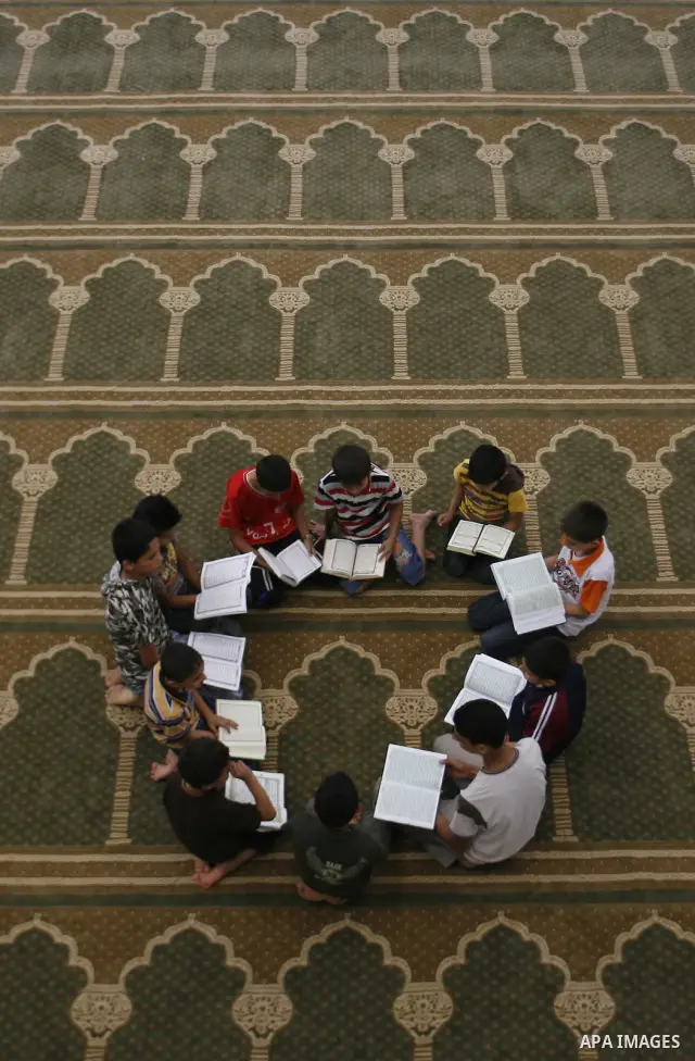 Palestinian boys read verses from the Quran during a class on how to read Islam's holy book, at a mosque in Rafah, southern Gaza city, on June 14, 2012. A summer camp in the Gaza Strip, 'Crown of Dignity IV', plans to te...