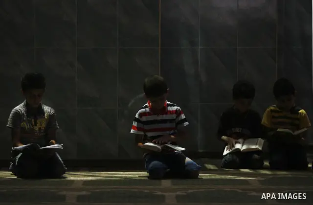 Palestinian boys read verses from the Quran during a class on how to read Islam's holy book, at a mosque in Rafah, southern Gaza city, on June 14, 2012. A summer camp in the Gaza Strip, 'Crown of Dignity IV', plans to te...