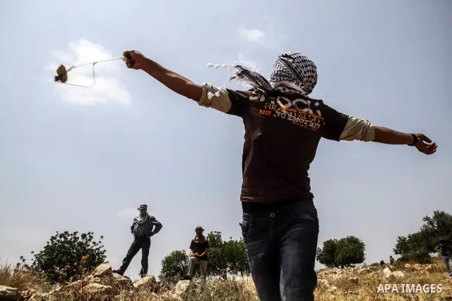 Palestinian protester hurls stones at Israeli soldiers during a weekly demonstration against Israel's controversial separation barrier in the West Bank village of Nilin on June 15, 2012. When completed, 85 percent of the...