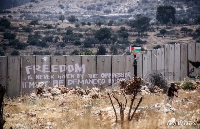 Palestinian protester holds national flags during a weekly demonstration against Israel's controversial separation barrier in the West Bank village of Nilin on June 15, 2012. When completed, 85 percent of the wall will h...