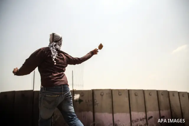 Palestinian protester hurls stones at Israeli soldiers during a weekly demonstration against Israel's controversial separation barrier in the West Bank village of Nilin on June 15, 2012. When completed, 85 percent of the...