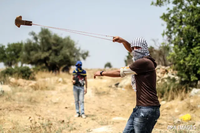 Palestinian protester hurls stones at Israeli soldiers during a weekly demonstration against Israel's controversial separation barrier in the West Bank village of Nilin on June 15, 2012. When completed, 85 percent of the...