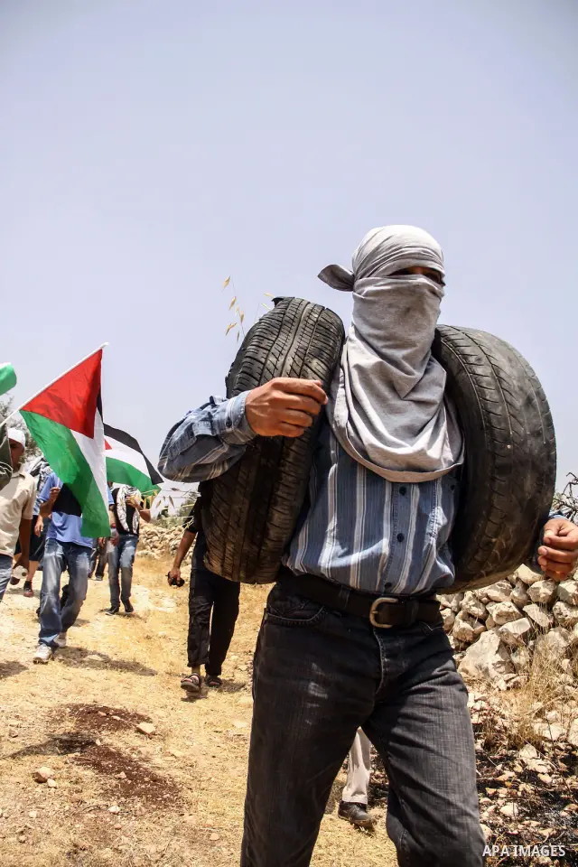 Palestinian protester holds tires during a weekly demonstration against Israel's controversial separation barrier in the West Bank village of Nilin on June 15, 2012. When completed, 85 percent of the wall will have been...
