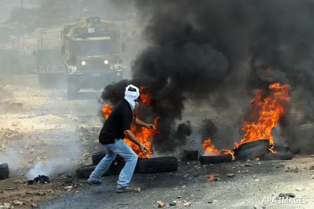 A Palestinian protester throws stones at an Israeli soldiers during clashes in the northern West Bank village of Kufr Qaddum, after the weekly protest against the expansion of the nearby Jewish settlement of Kdumim, on M...