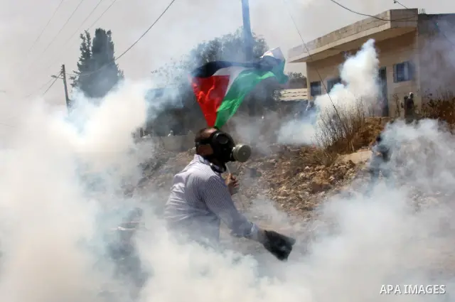 A Palestinian Protester returns a teargas towards Israeli soldiers during clashes in the northern West Bank village of Kufr Qaddum, after the weekly protest against the expansion of the nearby Jewish settlement of Kdumim...