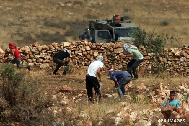 Palestinian protesters throw stones at Israeli soldiers during clashes in the West Bank village of Nabi Saleh, near Ramallah, on June 15, 2012, following a demonstration against the confiscation of Palestinian land to ex...