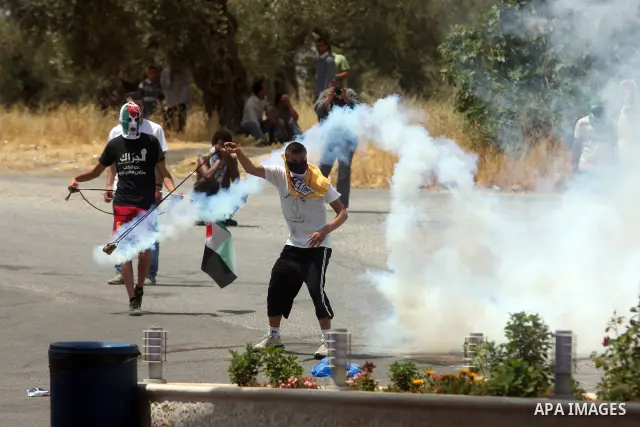 A Palestinian protester uses a sling shot to throw a tear gas canister, fired by Israeli soldiers, during clashes in the West Bank village of Nabi Saleh, near Ramallah, on June 15, 2012, following a demonstration against...