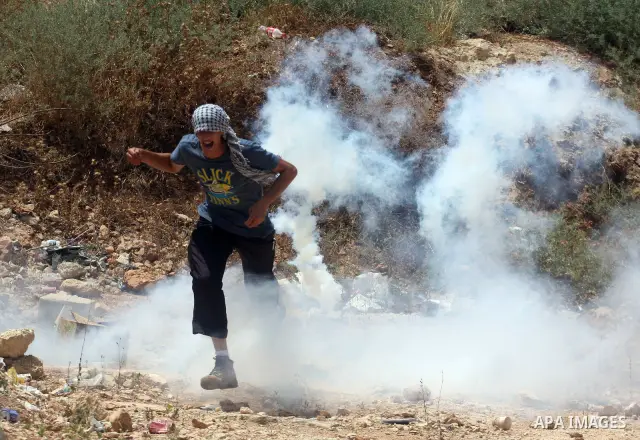 A Palestinian protester takes cover from tear gas fired by Israeli soldiers during clashes in the West Bank village of Nabi Saleh, near Ramallah, on June 15, 2012, following a demonstration against the confiscation of Pa...