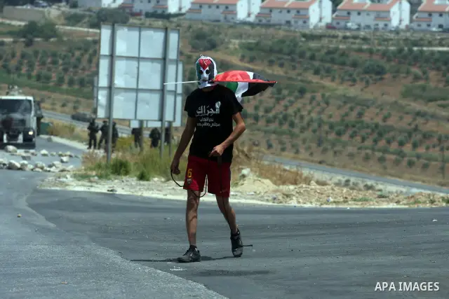 A Palestinian protester throws stones at Israeli soldiers during clashes in the West Bank village of Nabi Saleh, near Ramallah, on June 15, 2012, following a demonstration against the confiscation of Palestinian land to...