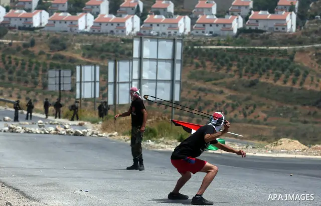 A Palestinian protester throws stones at Israeli soldiers during clashes in the West Bank village of Nabi Saleh, near Ramallah, on June 15, 2012, following a demonstration against the confiscation of Palestinian land to...