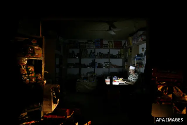 A Palestinian man works in a food shop and lighting a candle during a power outage in Rafah, southern Gaza Strip on June 16, 2012. Photo by Eyad Al Baba