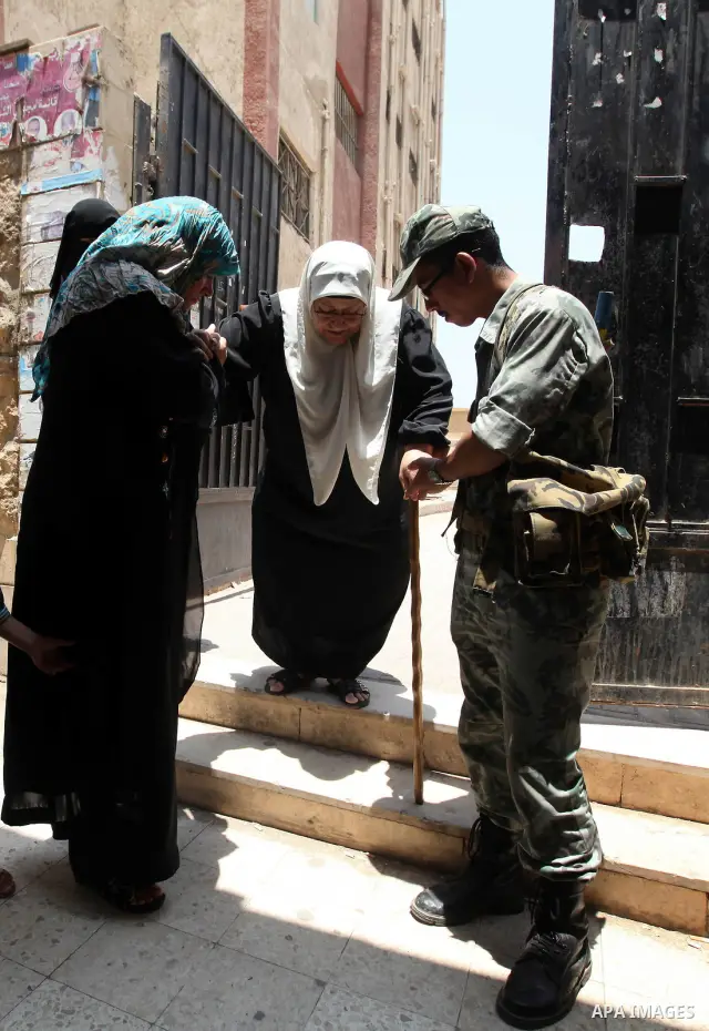An Egyptian army soldier helps a woman while leaving the polling station after voting during the second day of a run-off presidential election, in Cairo, Egypt, 17 June 2012. Egyptians began to vote in the final day of t...