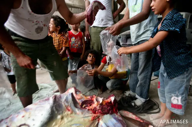 Palestinian children receive bags of horse meet in a poor neighborhood in the central Gaza Strip on 15 June 2012. The people of the poor neighborhood in the center of Gaza strip slaughter horses every twenty days, and di...