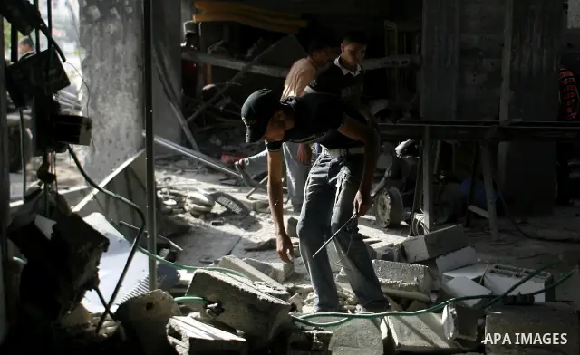 Palestinians survey a destroyed metal workshop after an Israeli air strike in Rafah, in the southern Gaza Strip June 18, 2012. Overnight on Sunday, Israeli aircraft carried out a series of strikes in the Gaza Strip in re...