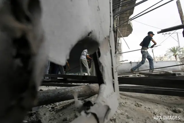Palestinians survey a destroyed metal workshop after an Israeli air strike in Rafah, in the southern Gaza Strip June 18, 2012. Overnight on Sunday, Israeli aircraft carried out a series of strikes in the Gaza Strip in re...