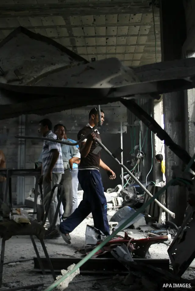 Palestinians survey a destroyed metal workshop after an Israeli air strike in Rafah, in the southern Gaza Strip June 18, 2012. Overnight on Sunday, Israeli aircraft carried out a series of strikes in the Gaza Strip in re...