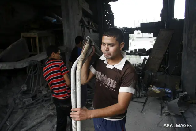 Palestinians survey a destroyed metal workshop after an Israeli air strike in Rafah, in the southern Gaza Strip June 18, 2012. Overnight on Sunday, Israeli aircraft carried out a series of strikes in the Gaza Strip in re...
