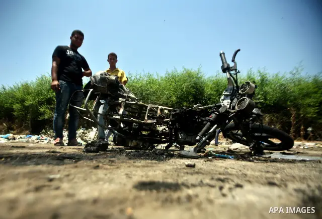 Palestinians look at a burnt out motorcycle that was destroyed in an Israeli air strike on north Gaza on June 18, 2012 killing two Palestinian men that were riding the motorbike near the Israeli border at the time. Witne...