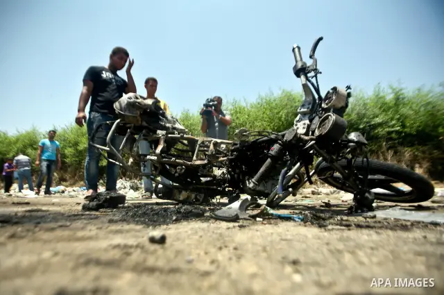 Palestinians look at a burnt out motorcycle that was destroyed in an Israeli air strike on north Gaza on June 18, 2012 killing two Palestinian men that were riding the motorbike near the Israeli border at the time. Witne...