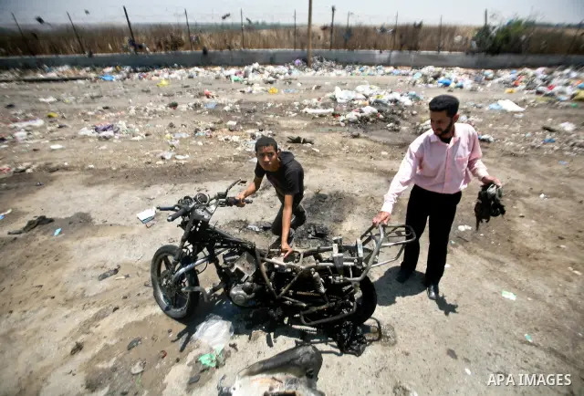 Palestinians look at a burnt out motorcycle that was destroyed in an Israeli air strike on north Gaza on June 18, 2012 killing two Palestinian men that were riding the motorbike near the Israeli border at the time. Witne...