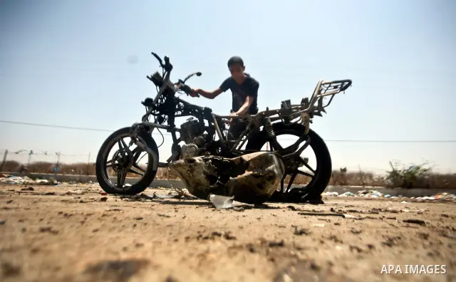 Palestinians look at a burnt out motorcycle that was destroyed in an Israeli air strike on north Gaza on June 18, 2012 killing two Palestinian men that were riding the motorbike near the Israeli border at the time. Witne...
