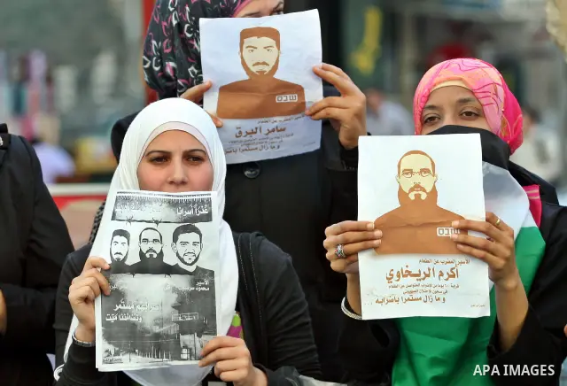 Palestinian protestors hold pictures of Palestinian prisoner Mahmoud Al-Sarsak, who is still refusing food for 96 days after a deal was made to end a mass prisoner hunger strike, during a demonstration in support him, in...