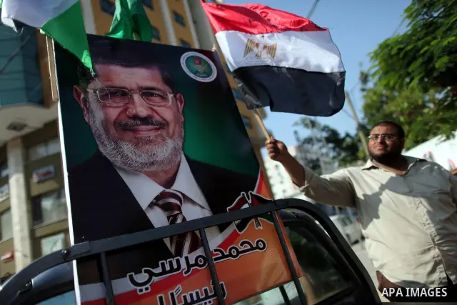 Palestinian Hamas supporters hold up Egyptian flags and the poster of the Muslim Brotherhood's presidential candidate Mohammed Morsi as they celebrate in the streets of Gaza City, 18 June 2012. Egypt's Muslim Brotherhood...