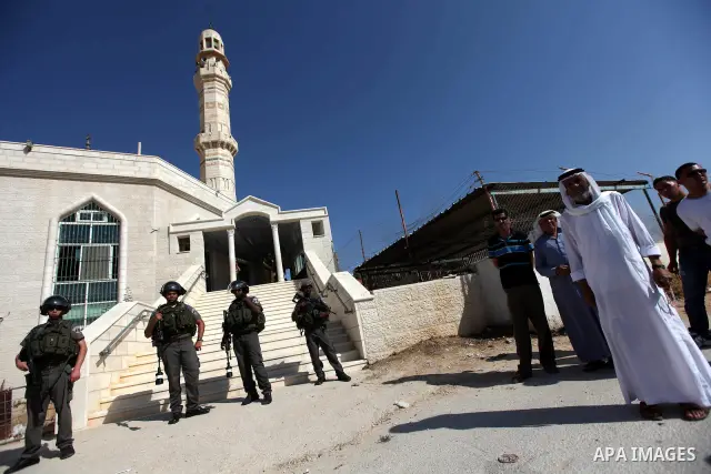 Israeli border police officers stand outside a damaged mosque in West Bank village of Jaba near Ramallah June 19, 2012. The mosque in the occupied West Bank was vandalised and set on fire early on Tuesday, in an attack P...