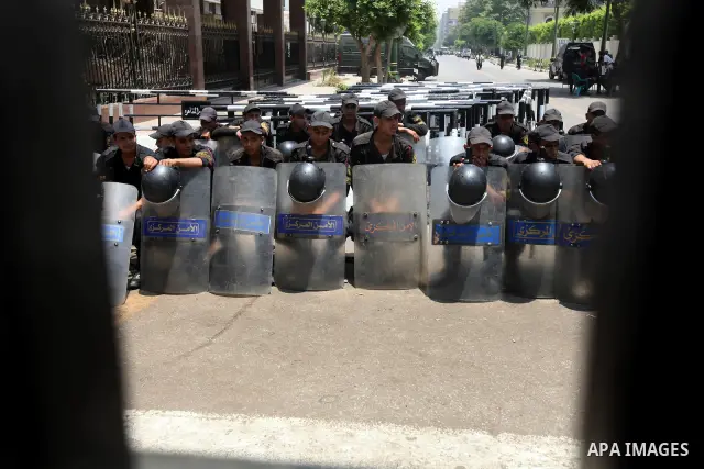 Egyptian riot police sit outside the parliament as protesters gather in Cairo, on June 19, 2012, after the Supreme Council of the Armed Forces (SCAF) issued a constitutional declaration on June 17, claiming legislative p...