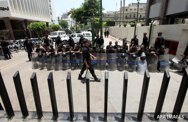 Egyptian riot police sit outside the parliament as protesters gather in Cairo, on June 19, 2012, after the Supreme Council of the Armed Forces (SCAF) issued a constitutional declaration on June 17, claiming legislative p...