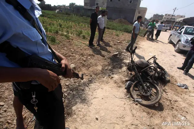A Hamas policeman stands near a motorcycle that was hit in an Israeli air strike in Dir al-Balah in the central Gaza Strip June 19, 2012. An Israeli army statement said the Israeli air force targeted Palestinian militant...