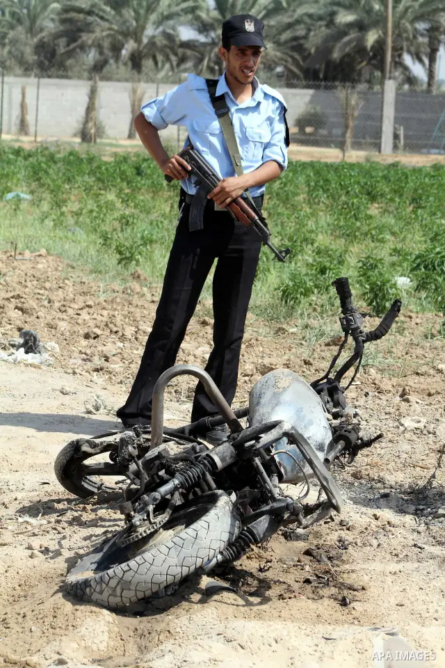 A Hamas policeman stands near a motorcycle that was hit in an Israeli air strike in Dir al-Balah in the central Gaza Strip June 19, 2012. An Israeli army statement said the Israeli air force targeted Palestinian militant...