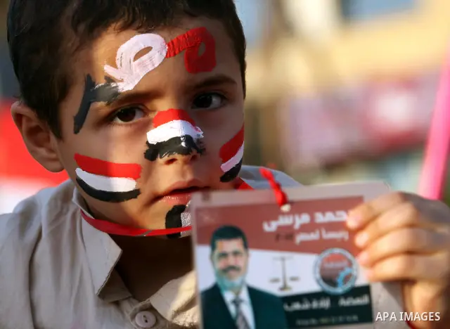 An Egyptian child hold a picture of Muslim Brotherhood presidential candidate Mohammed Mursi in Cairo's Tahrir Square on June 19, 2012 during a protest against the ruling military's bid to grab new powers, as both presid...