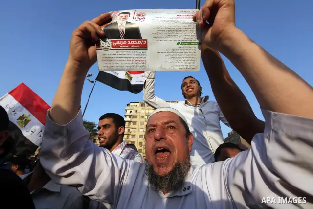 Egyptian supporters of Muslim Brotherhood presidential candidate Mohammed Mursi wave their national flag as they gather in Cairo's Tahrir Square on June 19, 2012 to protest against the ruling military's bid to grab new p...