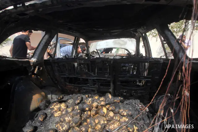 Palestinians are seen through a burnt cars of the potato outside a house after an Israeli air strike in Dir al-Balah in the central in the Gaza Strip June 20, 2012. The Israeli military said it had struck militant sites...
